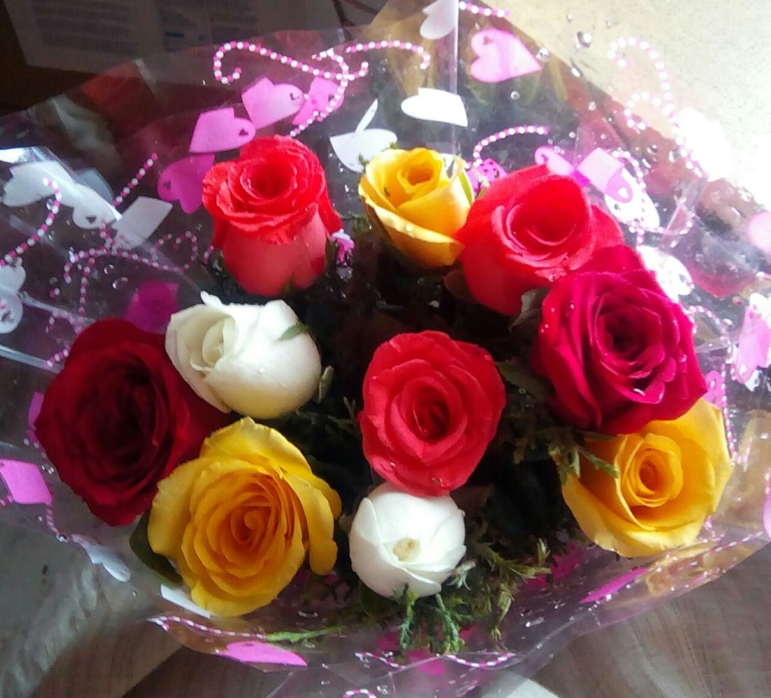 A multi-tone bouquet mixing white, pink, red, and yellow roses