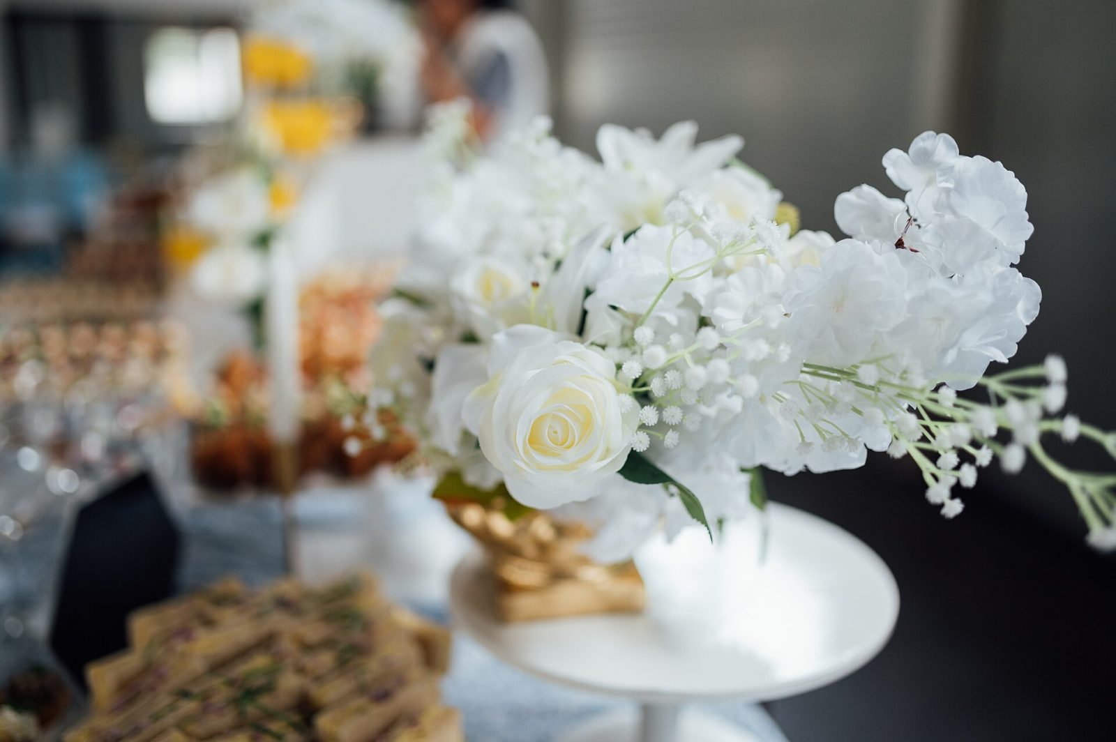 An elegant white flower arrangement standing in a gold vase